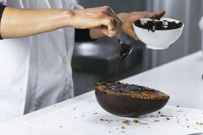 Midsection of man pouring coffee in cup on table