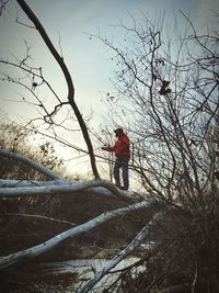 Man standing on bare tree during winter