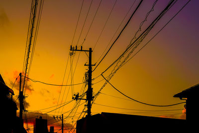 Low angle view of electricity pylon against sky during sunset