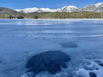 Scenic view of frozen lake by snowcapped mountains against sky