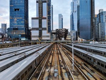 Railroad tracks amidst buildings in city against sky