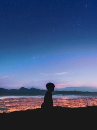 Silhouette man looking at sea against sky