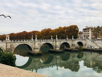 Arch bridge over river against cloudy sky