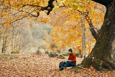 Man sitting on tree trunk during autumn