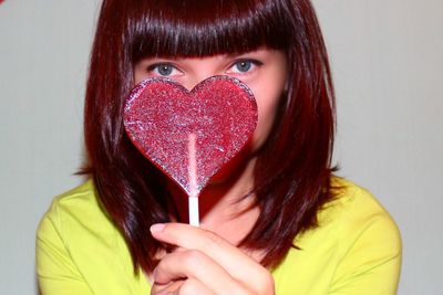 Close-up portrait of young woman holding heart