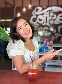 Portrait of a smiling young woman with drink in restaurant