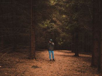 Young man standing by tree in forest