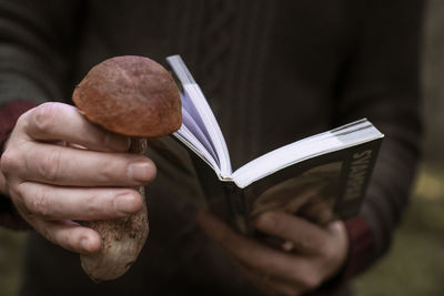 Hands holding mushroom and book