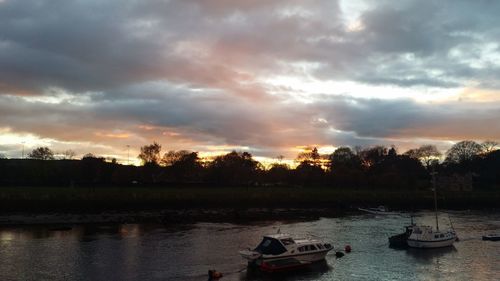 Boats in lake against sky during sunset