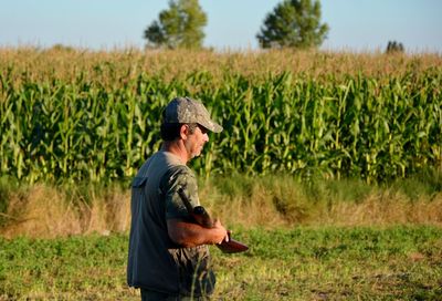 Man with weapon standing on agricultural field