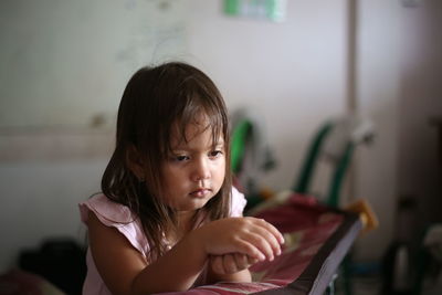 Girl looking away while sitting on book at home