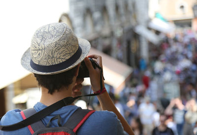 Rear view of man photographing camera in city