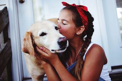 Girl kissing dog at home