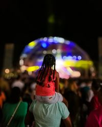 Rear view of man holding a girl against illuminated light