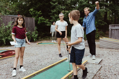 Full length of family playing miniature golf in backyard