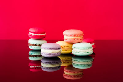 Close-up of multi colored macaroons on table against red background