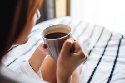 Midsection of woman holding coffee cup at home