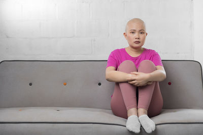 Portrait of girl sitting against pink wall