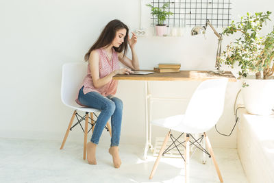 Woman sitting on table at home