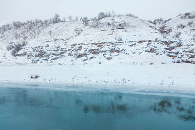 Hill covered by snow and frozen lake . winter frost scenery