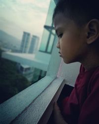 Close-up of boy looking through window