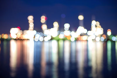 Defocused image of illuminated lights reflecting on lake at night