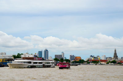 Boats in sea against sky in city