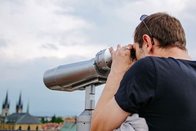 Man looking at city through binoculars