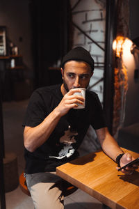 Portrait of young man sitting against wall