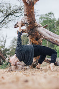 Low section of person on tree trunk on field
