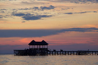 Silhouette lifeguard hut on beach against sky during sunset