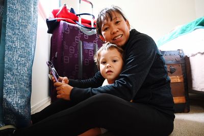 Portrait of mother and daughter sitting on floor