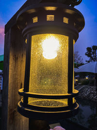 Close-up of illuminated lamp against sky at dusk