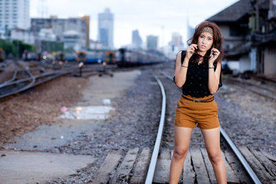 Portrait of fashionable woman standing on railroad track