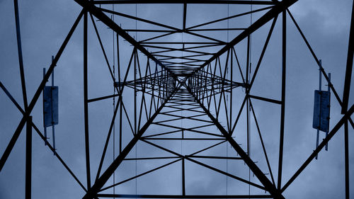Directly below shot of silhouette electricity pylon against sky