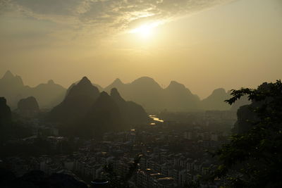 Aerial view of townscape by mountains against sky during sunset