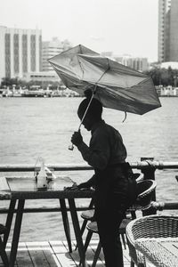 Waitress holding umbrella cleaning table at restaurant