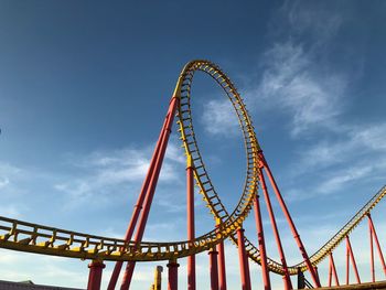 Low angle view of rollercoaster against blue sky