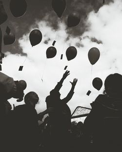 Silhouette children playing against cloudy sky