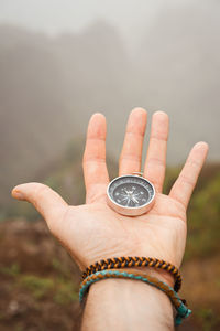 Close-up of person hand holding navigational compass over field