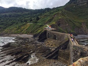 People on building by sea against mountain