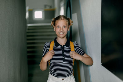 A cheerful teenage girl with a backpack and a folder hurries to school. back to school