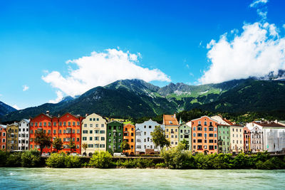 Buildings by lake against blue sky