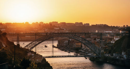 Dom luis bridge over river in city against orange sky 