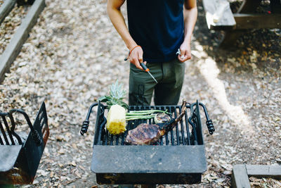 Low section of man standing on barbecue grill