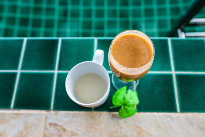 Close-up of fresh milk and fruit shakes on the floor by the pool .