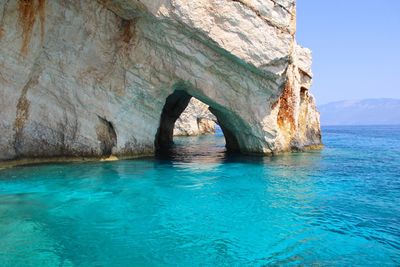 Rock formation in sea against blue sky