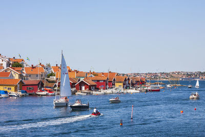 Sailboats in sea by buildings against clear sky