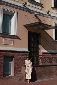 Young female model posing against building