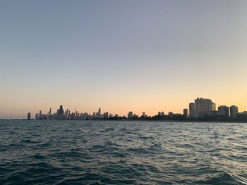 Scenic view of sea and buildings against clear sky